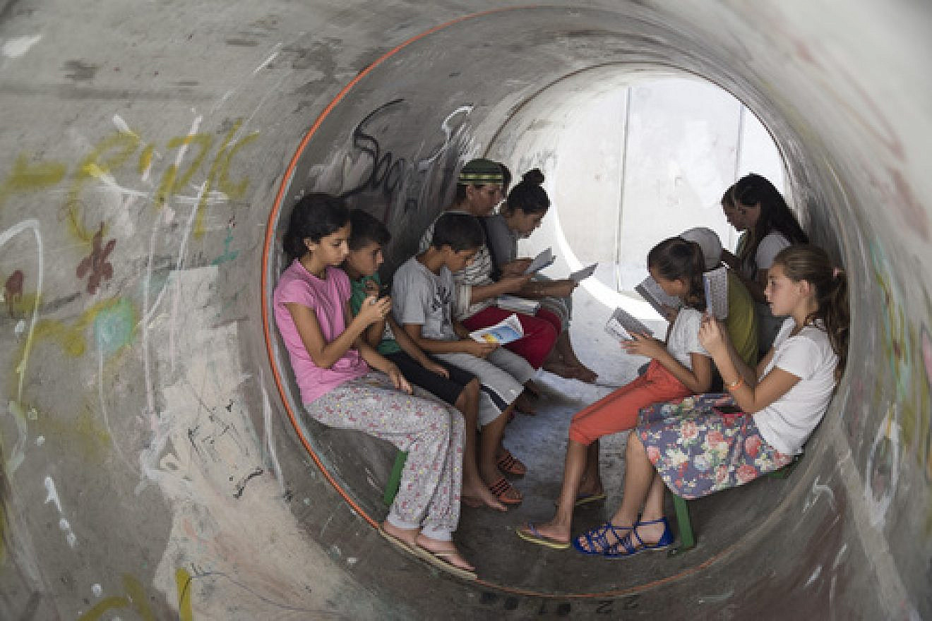 On July 11, 2014, the fourth day of “Operation Protective Edge,” Israelis in the southern town of Nitzan pray together inside a street-level bomb shelter in anticipation of a Code Red siren for incoming rockets. Credit: Hadas Parush/Flash90.