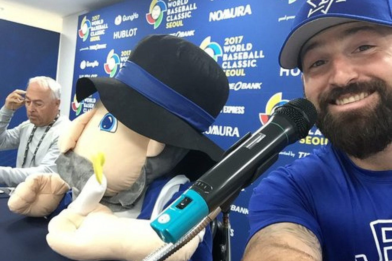 Cody Decker (right), a member of Team Israel at the World Baseball Classic (WBC), poses with the Israeli team’s mascot—the Hanukkah toy Mensch on a Bench (center)—at a WBC press conference. Credit: Cody Decker via Twitter.