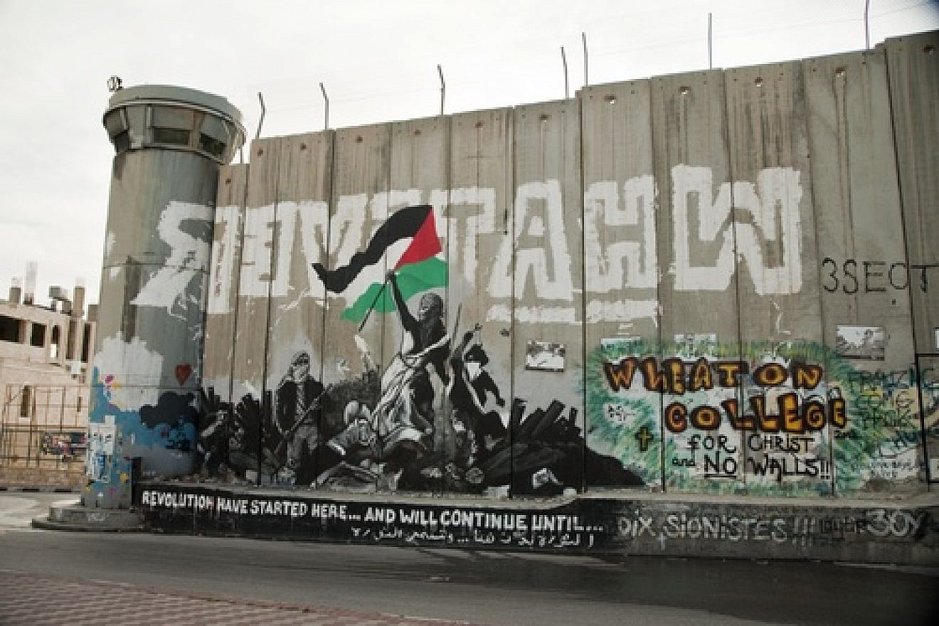 Anti-Israel graffiti on the Israeli security wall in Bethlehem. The wall comes under heavy criticism from those who claim it cuts off Palestinian communities from one another. Credit: Garry Walsh via Wikimedia Commons.