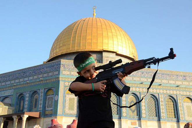 A Palestinian boy wearing a Hamas headband aims a toy gun during a rally after prayers at the Al-Aqsa mosque on the Temple Mount in Jerusalem, July 28, 2014. Photo by Sliman Khader/Flash90.