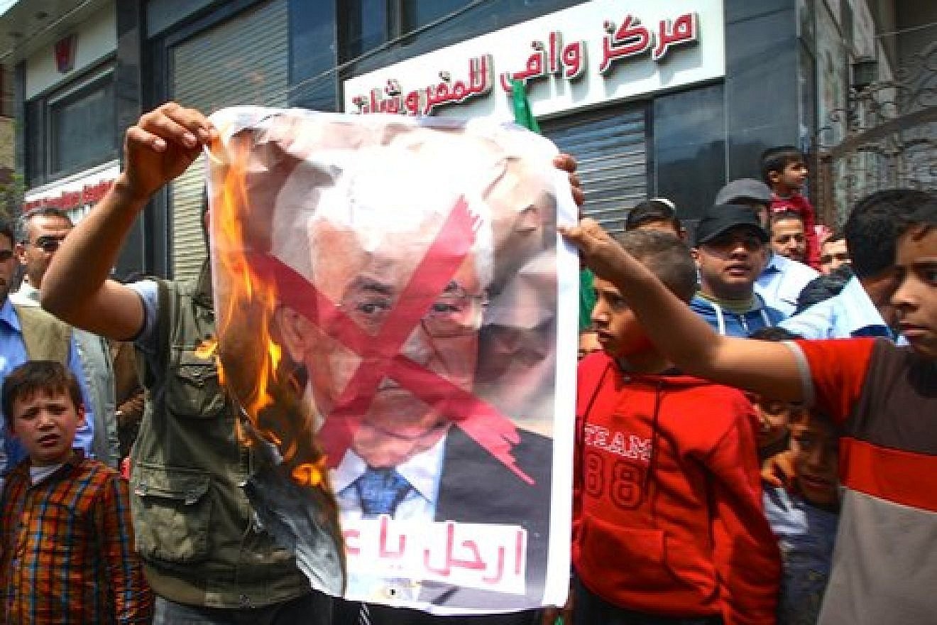 Palestinians burn a poster bearing a crossed-out image of Palestinian Authority (PA) President Mahmoud Abbas during a protest against both the Israeli government and the PA in the southern Gaza Strip, April 14, 2017. Credit: Abed Rahim Khatib/Flash90.