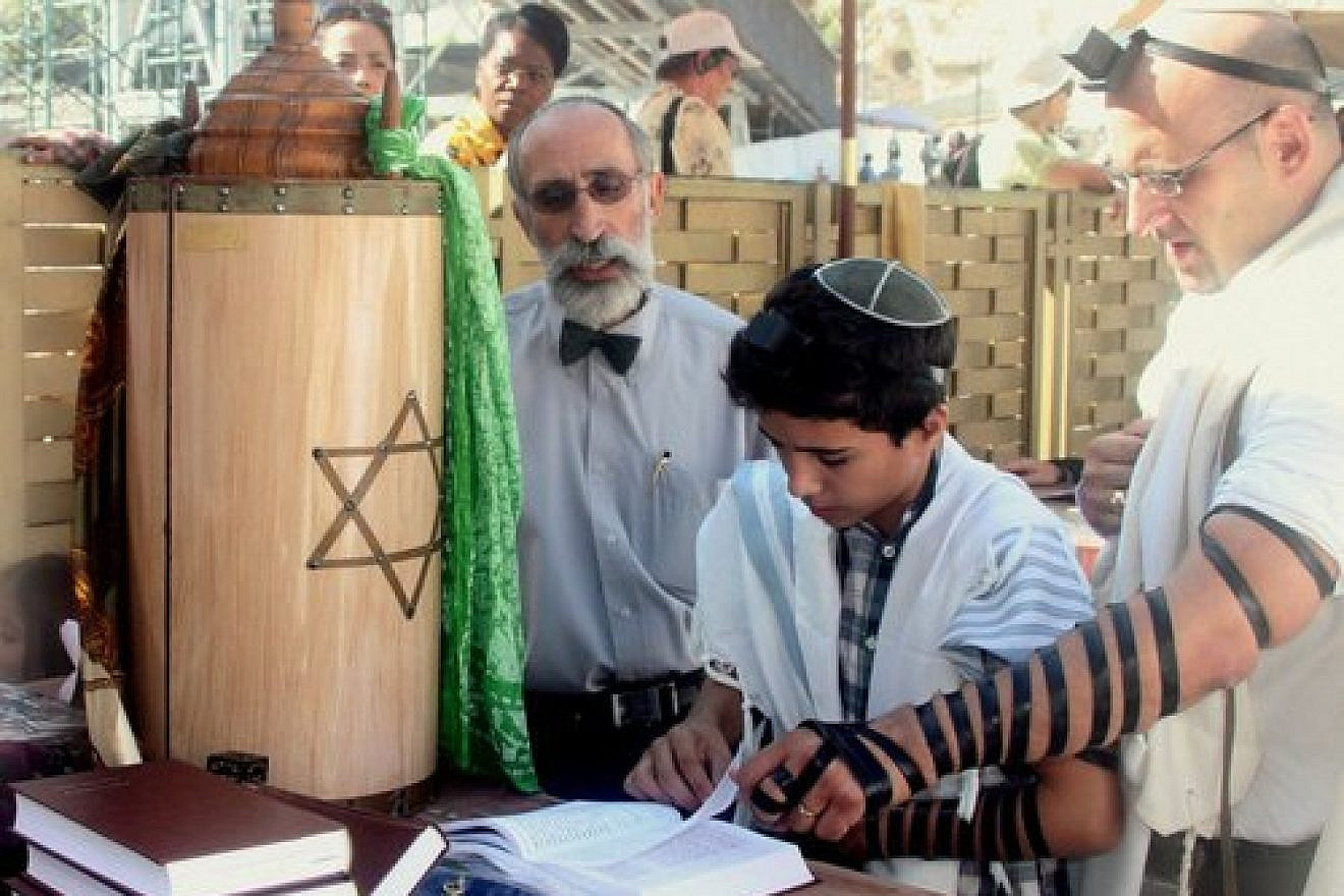 A bar mitzvah boy reads his Torah portion at the Western Wall in Jerusalem. Credit: Peter van der Sluijs via Wikimedia Commons.