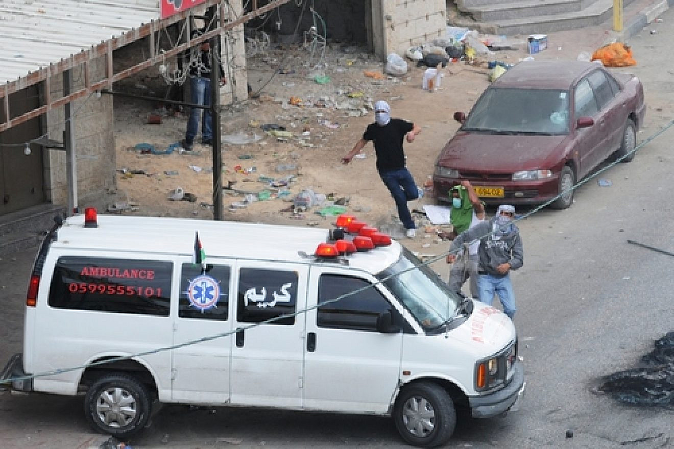 Click photo to download. Caption: Palestinians in Qalandiya use an ambulance for cover as they hurl rocks during a violent riot in May 2011. Credit: Israel Defense Forces.