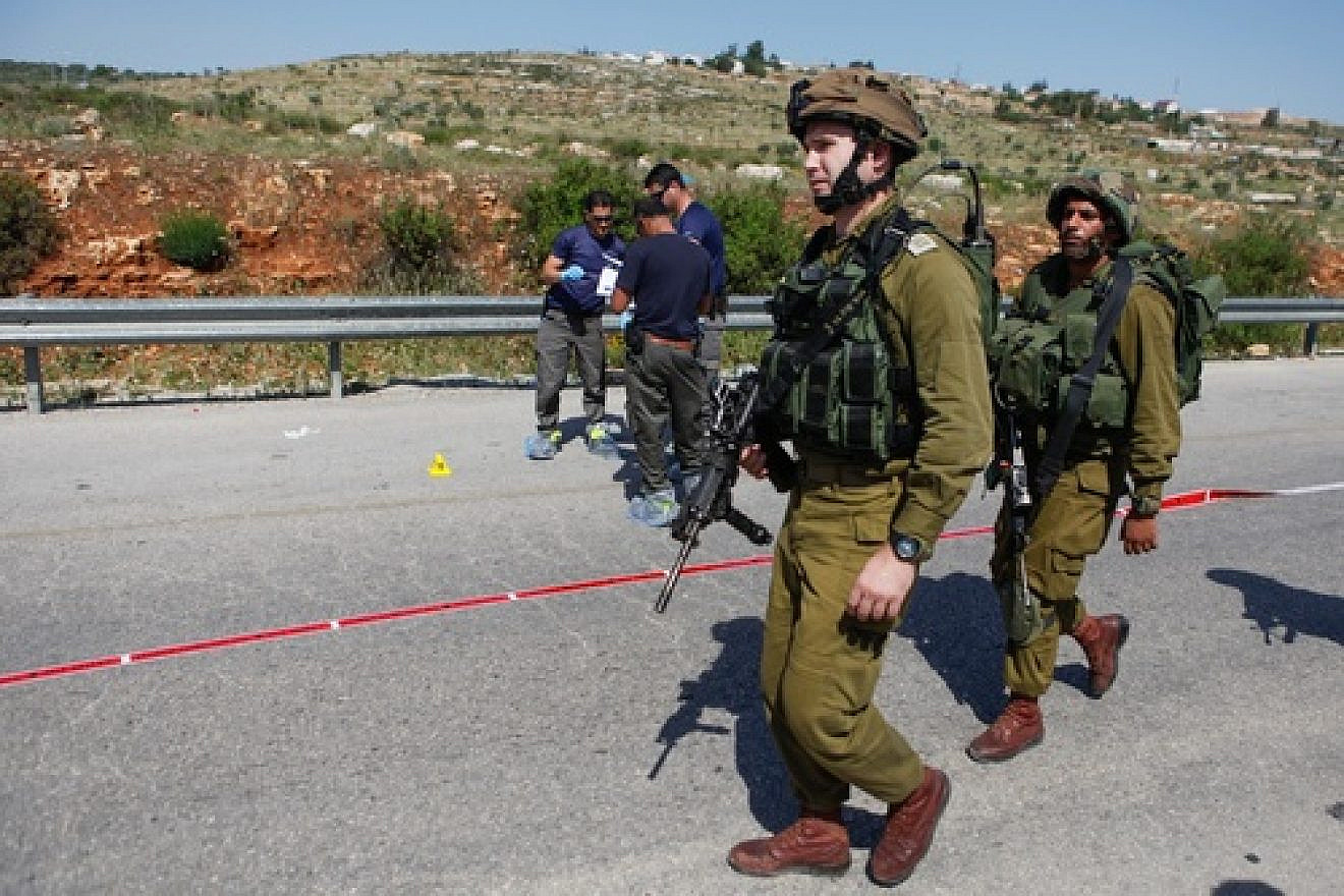 Israeli security forces inspect the site of a terror attack, at a bus stop at the Tapuach Junction on April 30, 2013. The Palestinian terrorist stabbed a 31-year-old Israeli man to death at a bus stop, police said. Credit: Flash90.
