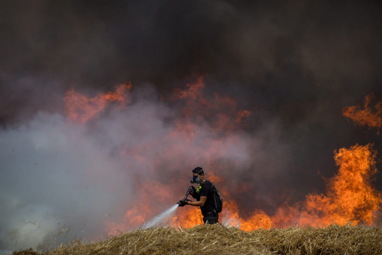 Israeli firefighters extinguish flames in a wheat field caused from incendiary kites flown by Palestinian protesters near the Gaza border on May 30, 2018. Photo by Yonatan Sindel/Flash90.