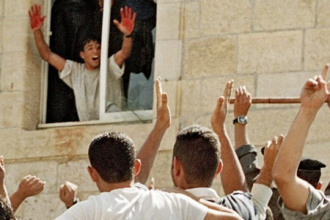 Aziz Salha, one of the participants in the 2000 lynching in Ramallah of two IDF reservists, holds up his blood-stained hands inside the Palestinian Authority's el-Bireh police station. Credit: Palestinian Media Watch.