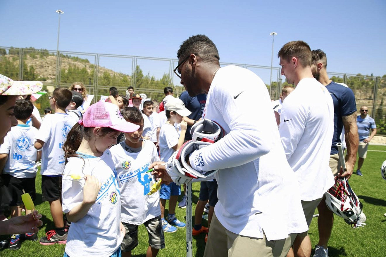 Team members sign shirts at a practice session days before the World Lacrosse Championship is set to being in Israel. Credit: The Israel Project.