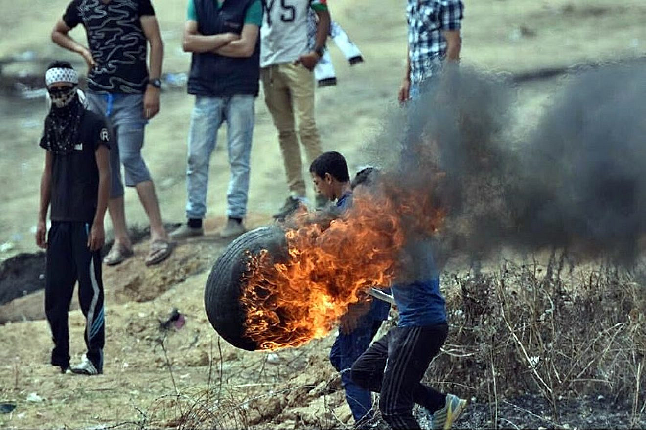Palestinians burn tires to throw over the Gaza border into Israel on May 4, 2018, as part of weekly riots led by Hamas terror organization since March 30, 2018. Credit: Wikimedia Commons.