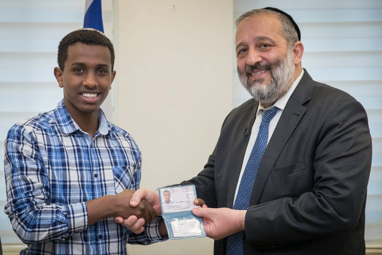 Sintayehu Shafrao from Ethiopia (left), who is competing in the annual International Bible Quiz in Israel, receives a National ID from Israel Minister of Interior Affairs Aryeh Deri during a ceremony at the Interior ministry office in Jerusalem on April 16, 2018. Photo by Yonatan Sindel/Flash90.