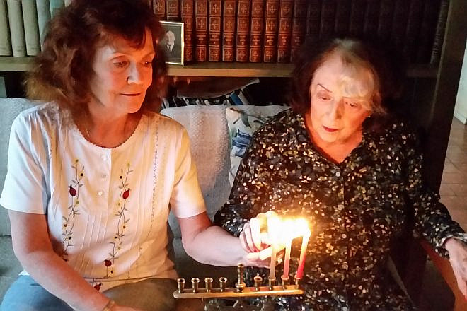 Margery B. Sterns (right), 96, a a longtime resident of San Francisco, lights the menorah with her daughter Sandra. Margery recalls her Russian immigrant parents lighting the menorah as one of her top memories of Hanukkah. Credit: Courtesy.