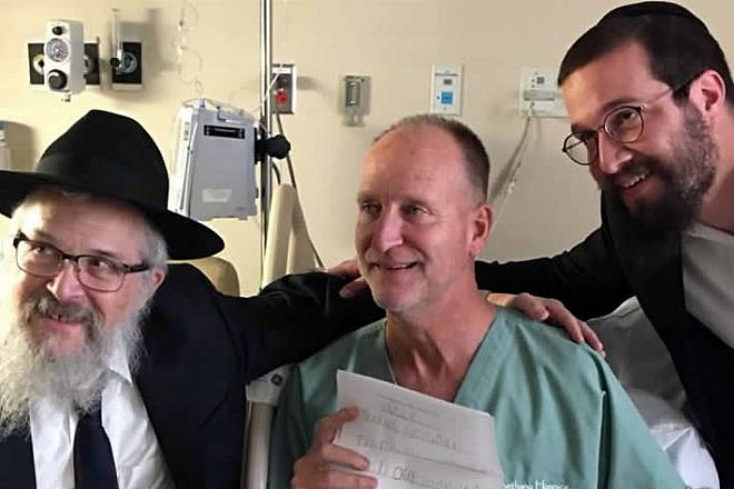 Officer Dan Mead, center, holds a letter of thanks from second-grade students at Yeshiva Schools of Pittsburgh. He is flanked by Rabbi Yisroel Rosenfeld, left, and Rabbi Henoch Rosenfeld. Credit: Chabad.org/News.