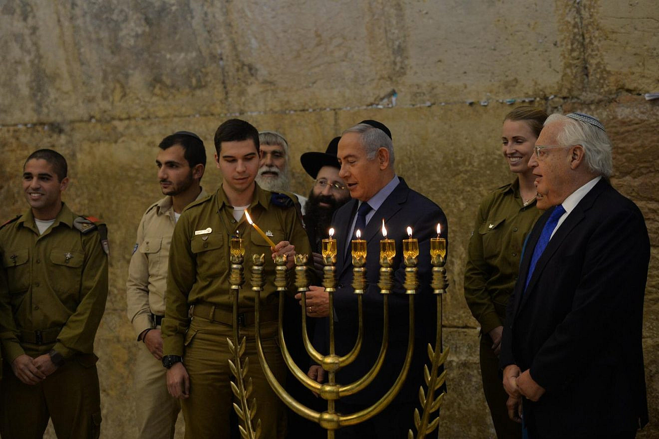 Israeli Prime Minister Benjamin Netanyahu lights the Hanukkah menorah at the Western Wall in Jerusalem on Dec. 6, 2018, with soldiers of the Israel Defense Forces and U.S. Ambassador to Israel David Friedman. Credit: Kobi Gideon/GPO.