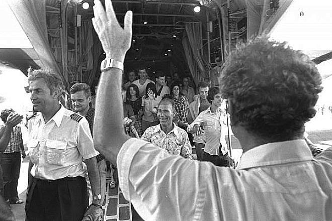 Israeli Foreign Minister Yigal Allon (back to camera) welcoming the rescued Air France passengers and crew, including pilot Michel Bacos (left), coming off an Israel Air Force Hercules plane at Ben-Gurion International Airport, July 1976. Credit: Moshe Milner/Israel Government Press Office.