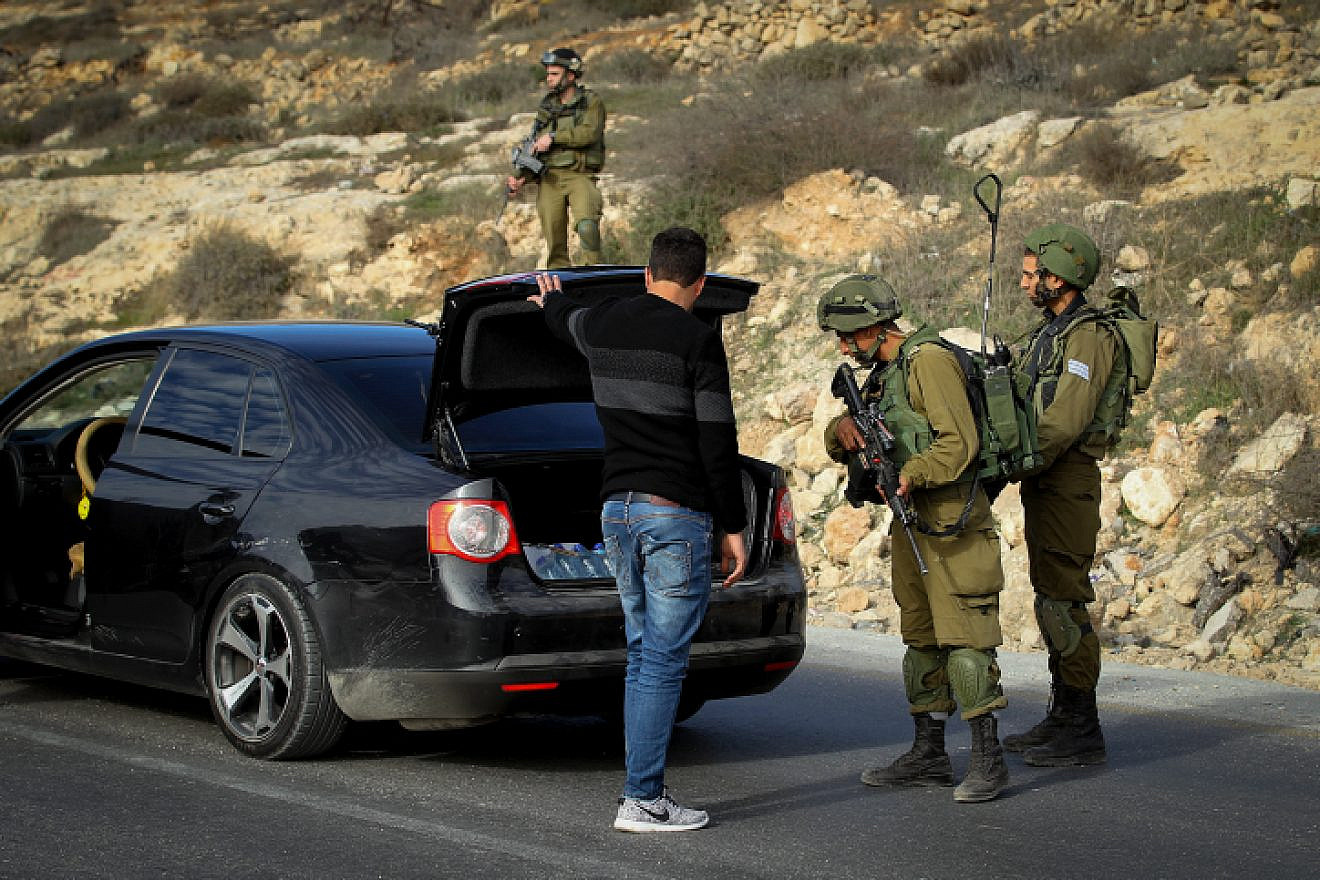 File photo: Israeli troops search Palestinians at a temporary checkpoint near Hebron in Judea, Jan. 20, 2017. Photo by Wisam Hashlamoun/Flash90.