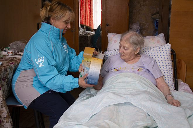 Continuing JDC’s long-held tradition of matzah delivery for Passover, a volunteer provides matzah to an elderly client in Odessa, Ukraine. Credit: Courtesy.