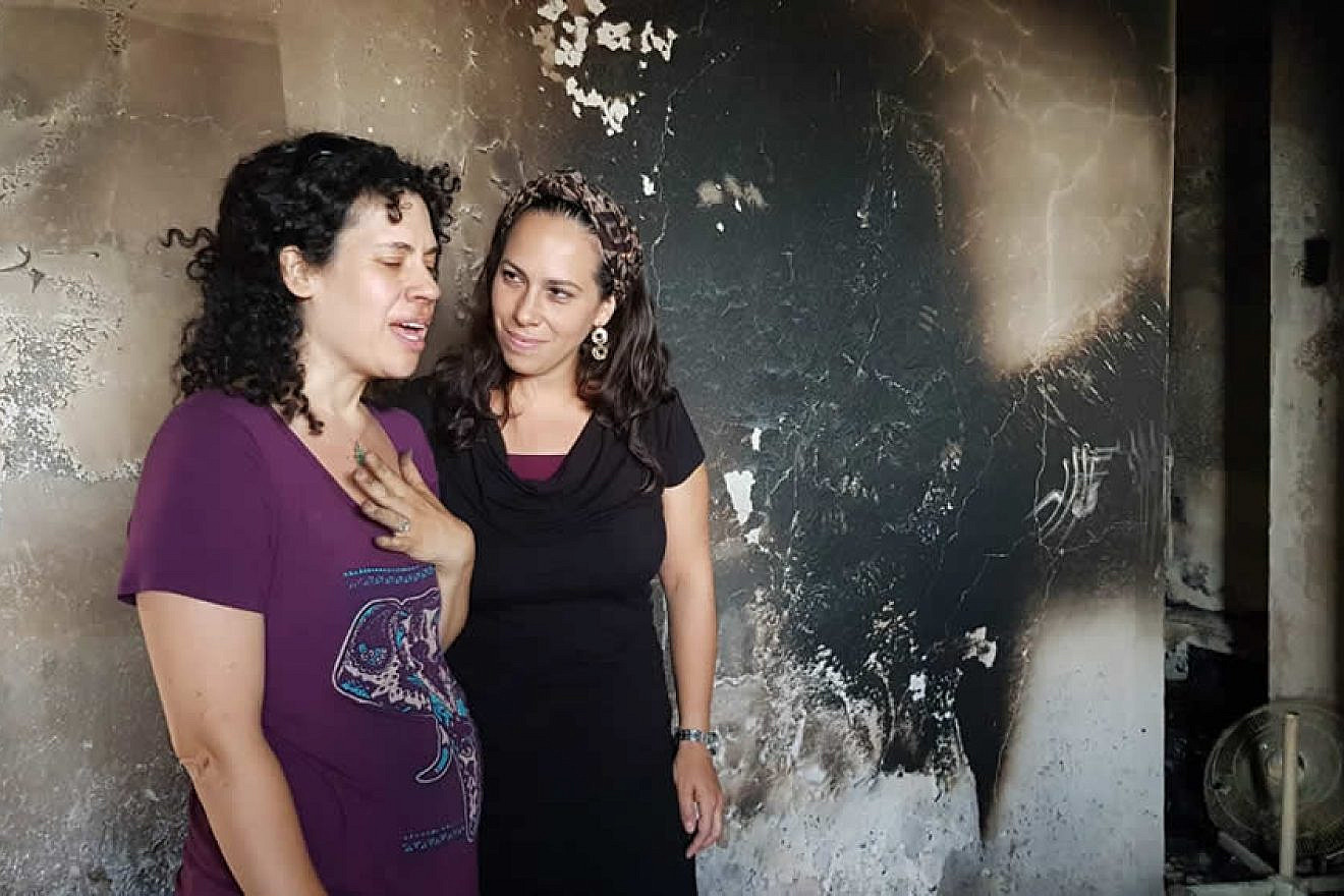 Dari Carlebach (left), daughter of the late Rabbi Shlomo Carlebach, and Yael Eckstein, daughter of the late Rabbi Yechiel Eckstein, examine damage by fire to nearly 50 homes in moshav Mevo Modi’im, May 27, 2019. Credit: IFCJ.