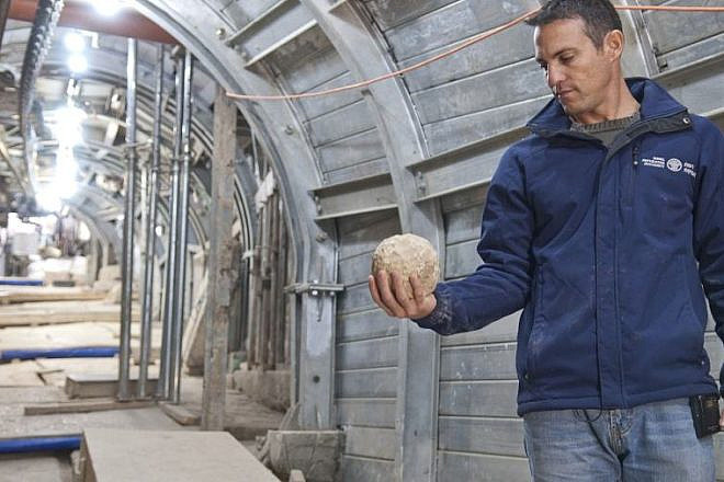 Nachshon Zenton, one of the directors of the Pilgrimage Road excavation in Jerusalem's City of David, holds a catapult projectile apparently used during the Great Jewish Revolt. Credit: Shai Halawi, Israel Antiquities Authority.