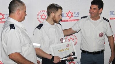 Magen David Adom director general Eli Bin (right) presents Dvir Shnerb with his EMT certificate. Credit: Magan David Adom.