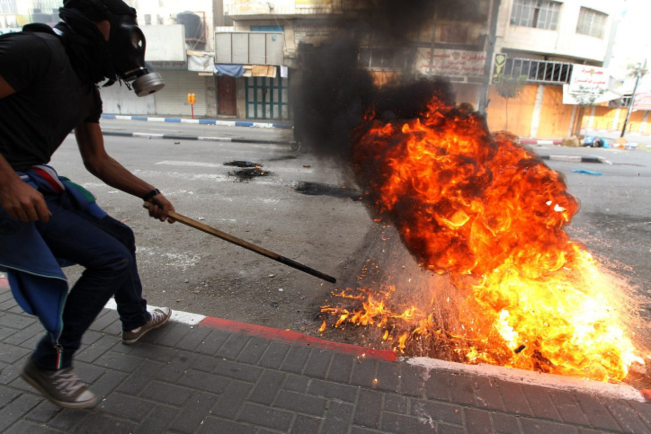 A Palestinian demonstrator uses a slingshot to hurl stones at Israeli troops during clashes as Palestinians call for a “Day of Rage” in response to U.S. President Donald Trump's recognition of Jerusalem as Israel's capital, in the West Bank city of Hebron, Dec. 22, 2017. Photo by Wisam Hashlamoun/Flash90.