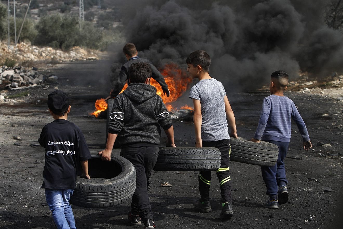 Palestinian boys carry tires to burn as part of clashes with Israeli forces during a protest in the village of Kfar Qaddum, near the West Bank city of Nablus, on Nov. 1, 2019. Both the Palestinian Authority and Hamas are roundly criticized for using children in violent protests. Photo by Nasser Ishtayeh/Flash90.