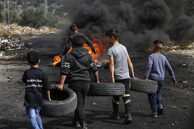 Palestinian boys carry tires to burn as part of clashes with Israeli forces during a protest in the village of Kfar Qaddum, near the West Bank city of Nablus, on Nov. 1, 2019. Both the Palestinian Authority and Hamas are roundly criticized for using children in violent protests. Photo by Nasser Ishtayeh/Flash90.