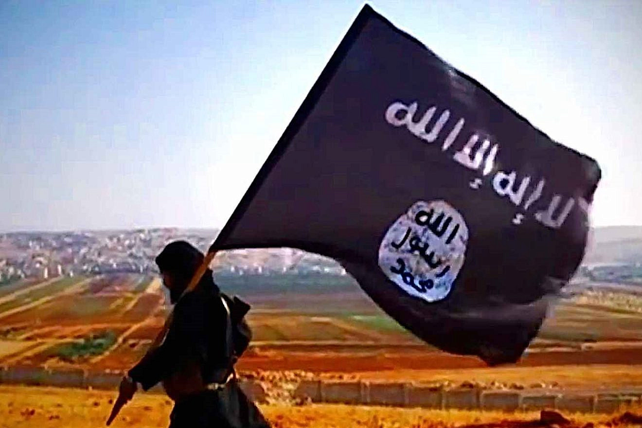A terrorist carries the Islamic State's flag overlooking Dabiq in Syria in 2013. Source: Wikimedia Commons.