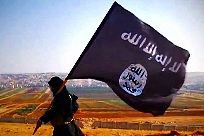 A terrorist carries the Islamic State's flag overlooking Dabiq in Syria in 2013. Source: Wikimedia Commons.