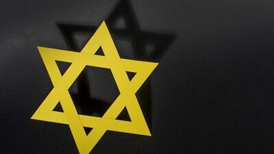 Yellow Star of David with shadow on black background. Credit: Ausra Barysiene/Shutterstock.