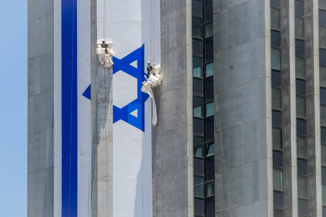 Israeli workers hang a large Israeli flag in Ramat Gan, June 8, 2022. Photo by Avshalom Sassoni/Flash90.