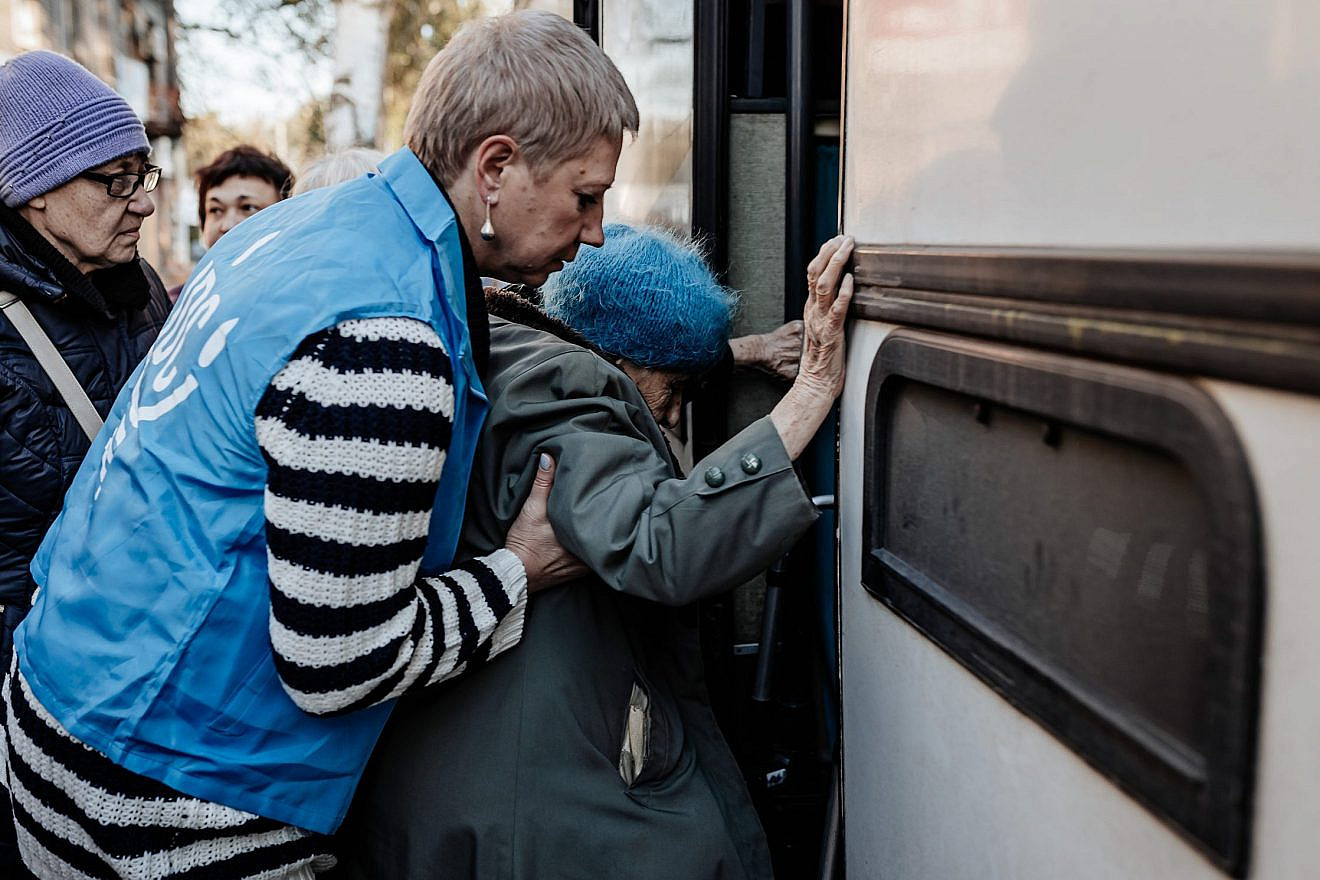A JDC Jewish community volunteer helps an elderly woman onto a bus that is part of a JDC evacuation convo out of the city of Dnipro during the height of the conflict. Photo by Misha Kovalev.
