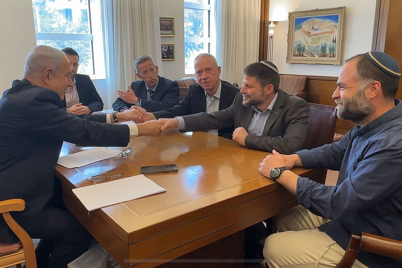 Israeli Prime Minister Benjamin Netanyahu (left), Defense Minister Yoav Gallant (shaking Netanyahu's left hand) and Minister in the Defense Ministry Bezalel Smotrich (shaking Netanyahu's right hand) sign a document of understandings on the division of responsibility in the Defense Ministry, on Feb. 23, 2023. Credit: Courtesy.