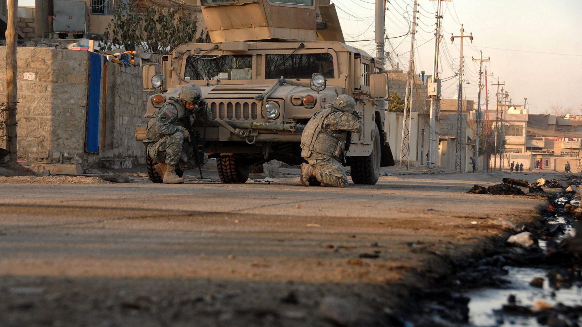 U.S. Army soldiers, attached to Heavy Company, 3rd Squadron, 3rd Armored Cavalry Regiment, take cover behind their vehicle as small-arms fire opens up in the distance in Mosul, Iraq, Jan. 17, 2008. Credit: Spc. Kieran Cuddihy/U.S. Army photo.