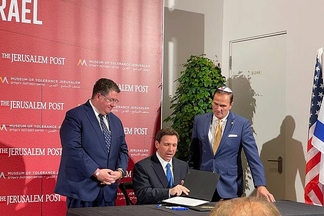 Florida State Reps. Randy Fine (left) and Mike Caruso look down as Gov. Ron DeSantis signs a “public nuisances” bill, HB 269, in Jerusalem on April 27, 2023. Credit: Orthodox Union.