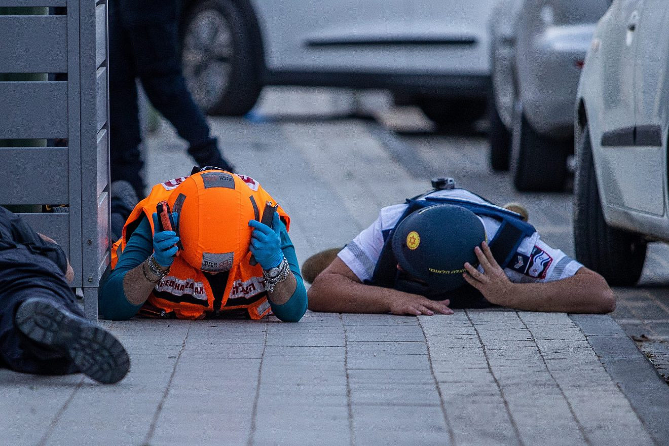 Israeli police and emergency responders take cover as a siren warns of incoming rockets from the Gaza Strip, May 11, 2023. Photo by Oren Ben Hakoon/Flash90.