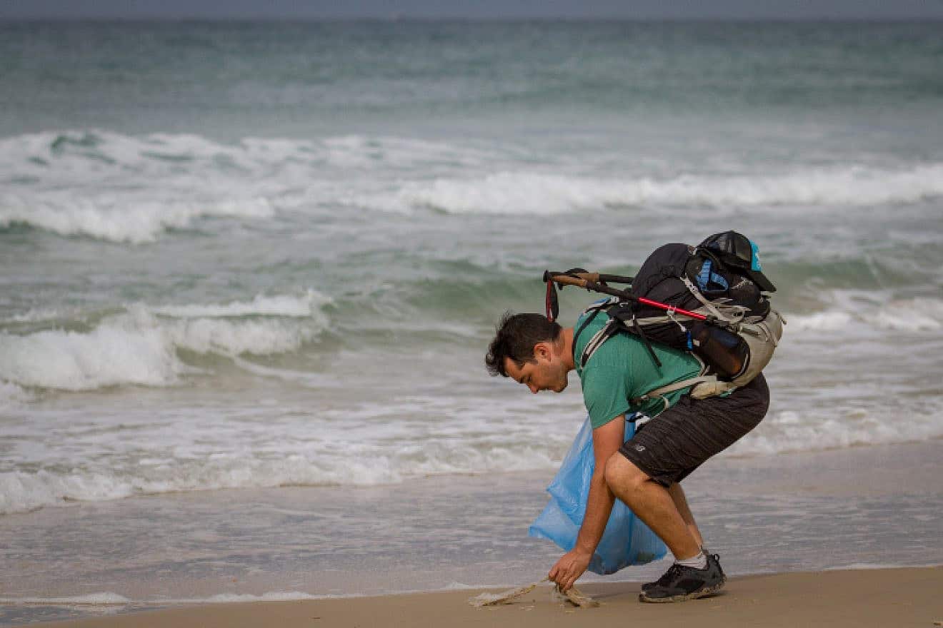 Israeli blogger Gil Drori pick up plastic bags at Beit Yanai Beach, north of Netanya, as part of his effort to raise awareness of the harmful effects of disposable plastic, Nov. 23, 2018. Photo by Meir Vaknin/Flash90.