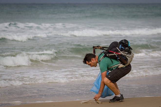Israeli blogger Gil Drori pick up plastic bags at Beit Yanai Beach, north of Netanya, as part of his effort to raise awareness of the harmful effects of disposable plastic, Nov. 23, 2018. Photo by Meir Vaknin/Flash90.