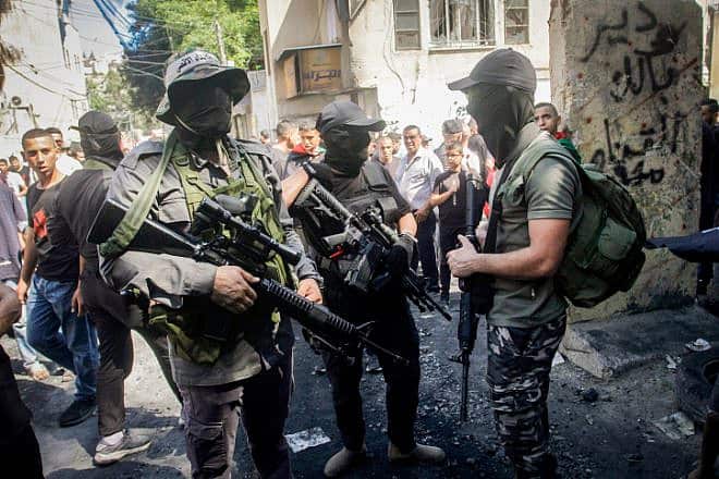 Palestinian gunmen near a damaged house following an Israeli military raid at the Nur Shams refugee camp, east of Tulkarm, on Sept. 5, 2023. Photo by Nasser Ishtayeh/Flash90.