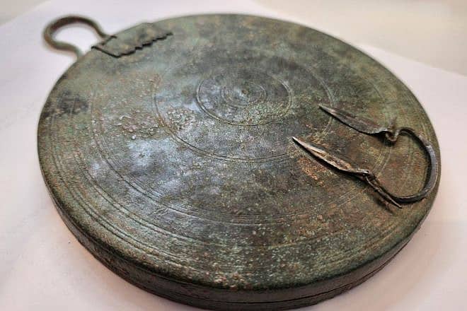 The ancient bronze folding mirror found in a Jerusalem tomb. Photo by Yoli Schwartz/Israel Antiquities Authority.