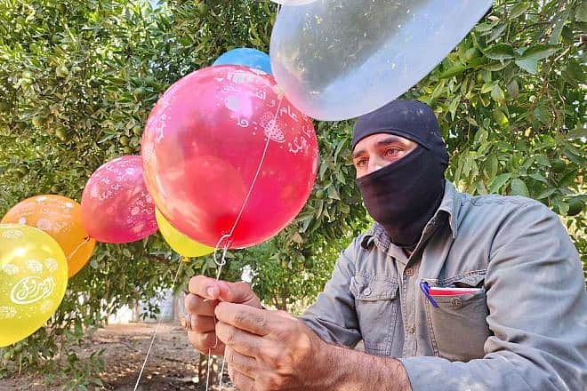 Masked terrorists prepare helium balloons with incendiary material to be flown into Israel, aiming to cause casualties and damage, on Sep. 22, 2023. Photo by Majdi Fathi/TPS.