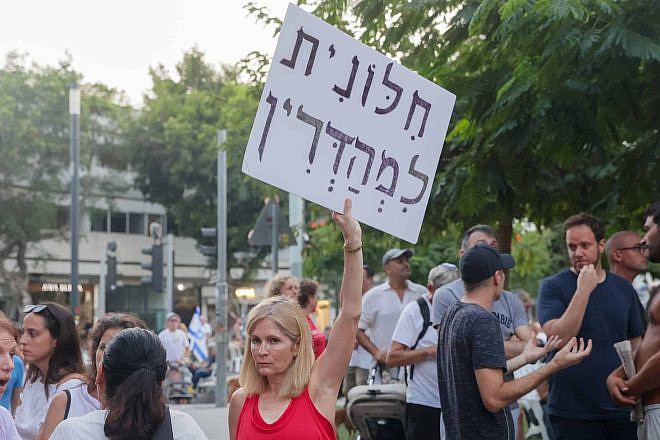A woman holds a sign reading "Strictly secular" at a demonstration against a gender-segregated Yom Kippur prayer service at Dizengoff Square in Tel Aviv on Yom Kippur, Sept. 25, 2023. Photo by Itai Ron/Flash90.