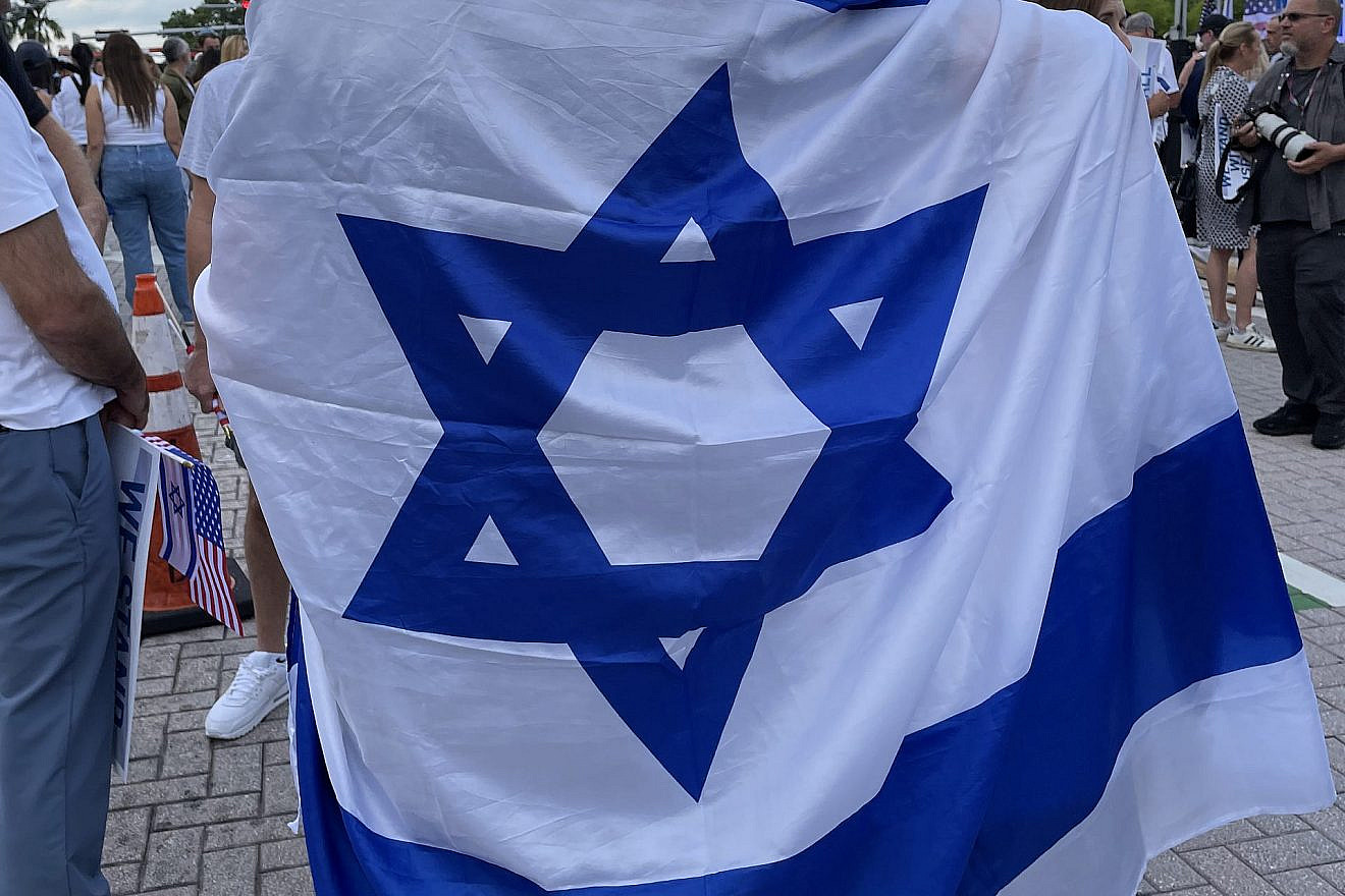 Carlos Frost and his son, Aaron Frost, draped themselves with an Israeli flag at a solidarity rally for Israel in Miami Beach, Fla., on Oct. 10, 2023. Photo by Sergio Carmona.