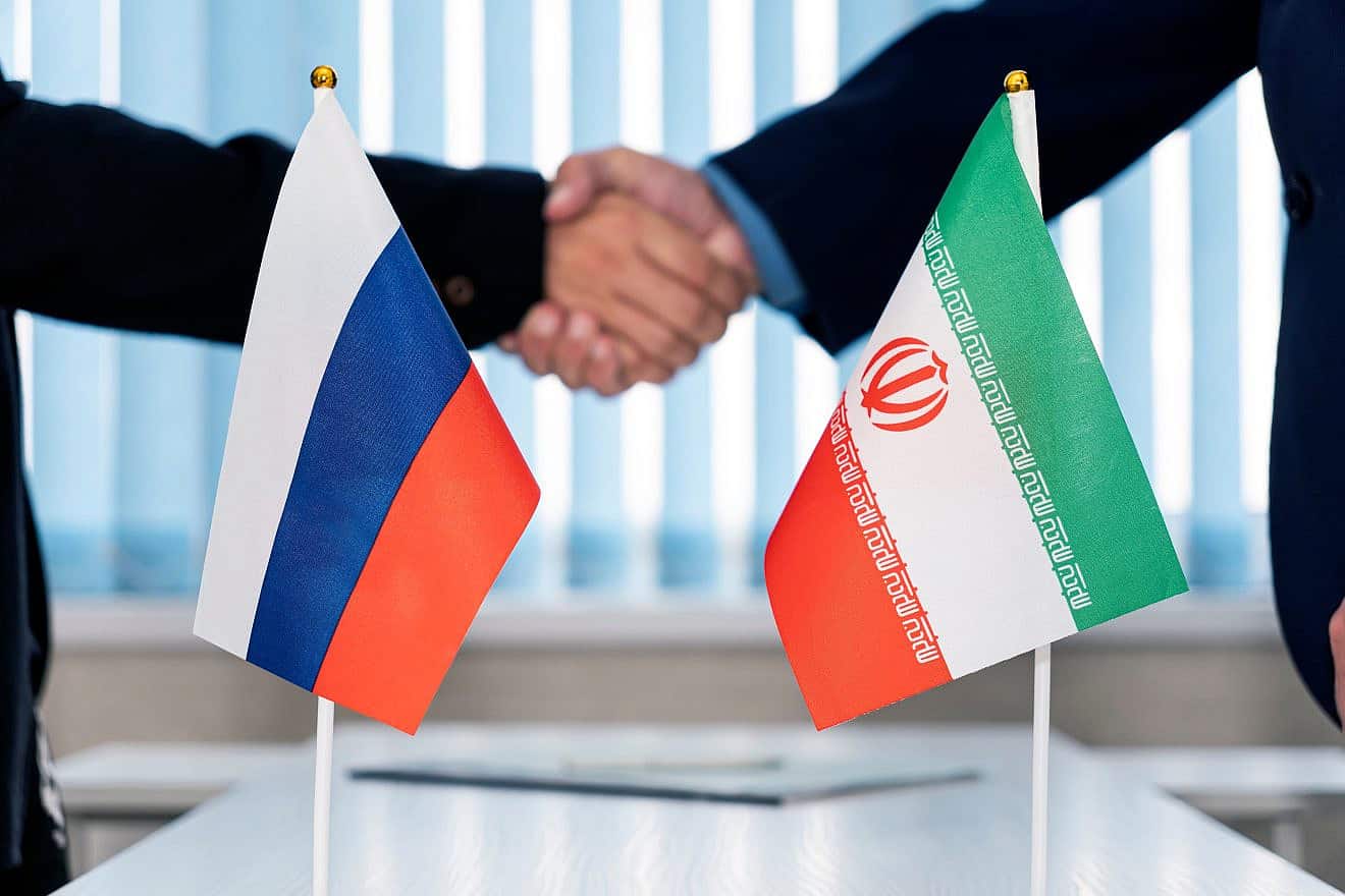 Flags of Russia and Iran on a table in an international negotiation room. Credit: Melnikov Dmitriy/Shutterstock.