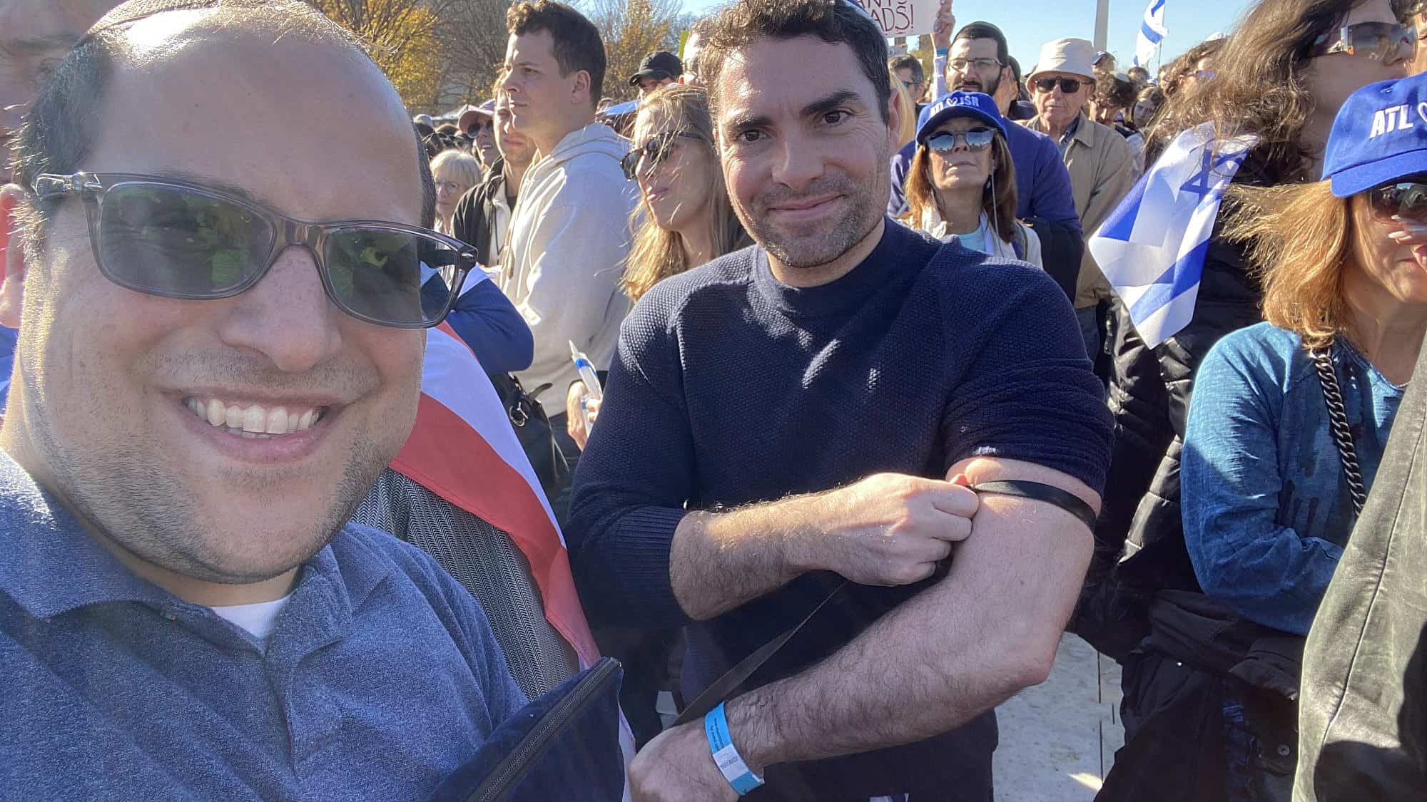 The comedian Eli Lebowicz (left) helped fellow participants at the "March for Israel" wrap tefillin on Nov. 14, 2023. Credit: EliComedy.com.