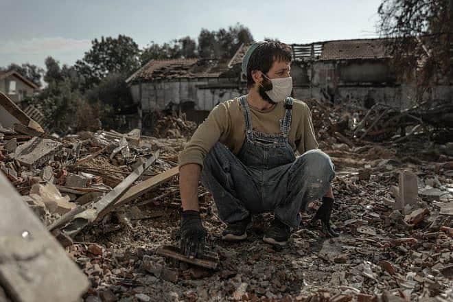 A man whose father was murdered by Hamas terrorists on Oct. 7 searches the rubble of his home for family mementos in Kibbutz Be'eri, Nov. 30, 2023. Photo by Chen Schimmel/Flash90.