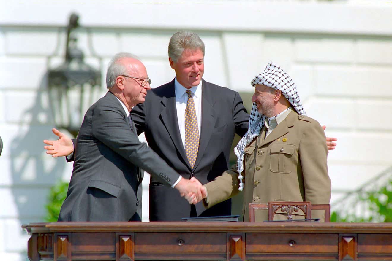 U.S. President Bill Clinton looks on as Israeli Prime Minister Yitzhak Rabin and PLO head Yasser Arafat shake hands at the signing of the Oslo Accords on Sept. 13, 1993. Credit: William J. Clinton Presidential Library/National Archives & Records Administration.