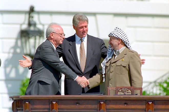 U.S. President Bill Clinton looks on as Israeli Prime Minister Yitzhak Rabin and PLO head Yasser Arafat shake hands at the signing of the Oslo Accords on Sept. 13, 1993. Credit: William J. Clinton Presidential Library/National Archives & Records Administration.