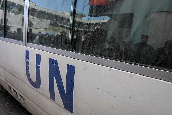 Palestinians looking for food at an UNRWA school are reflected in the windows of a United Nations vehicle in Gaza on Jan. 24, 2024. Credit: Anas-Mohammed/Shutterstock.