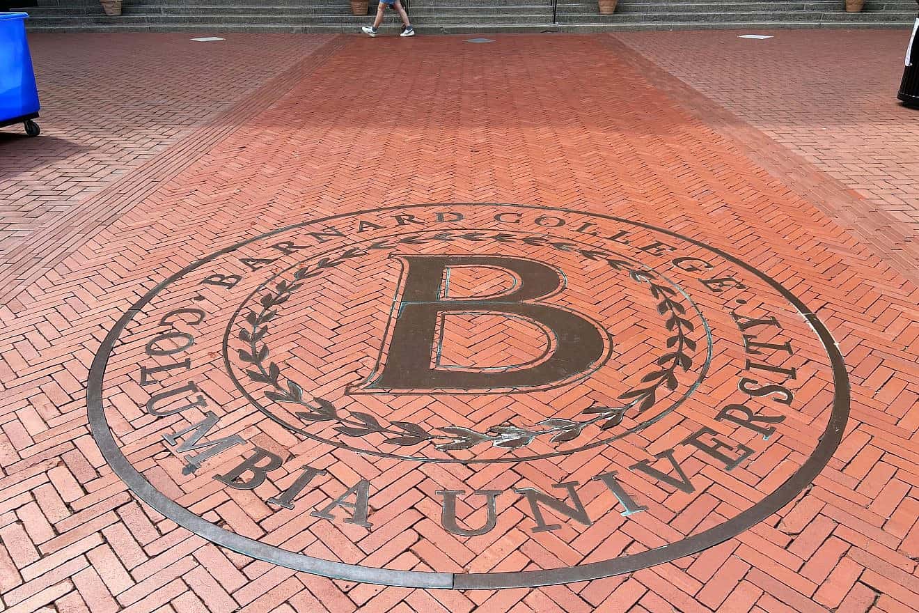 Close-up of bronze letter “B” surrounded by a laurel wreath logo embedded in ground of paved brick entrance of Barnard College, the sister school of Columbia University, in New York City. Credit: Here Now/Shutterstock.