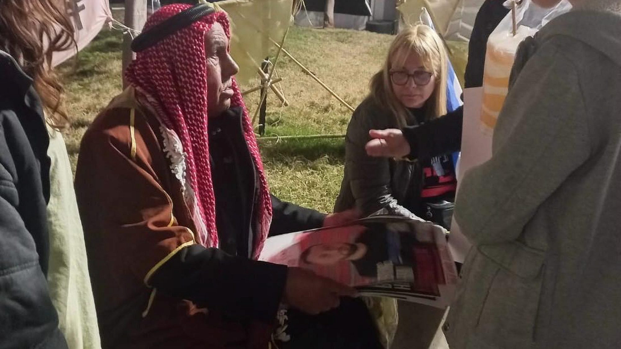 Sheikh Khaled, a resident of Rahat, shows pictures of relatives being held by Hamas in Gaza to supporters and other hostages' families at Tel Aviv's Hostage Square, on Feb. 10, 2024. Photo by Amelie Botbol.