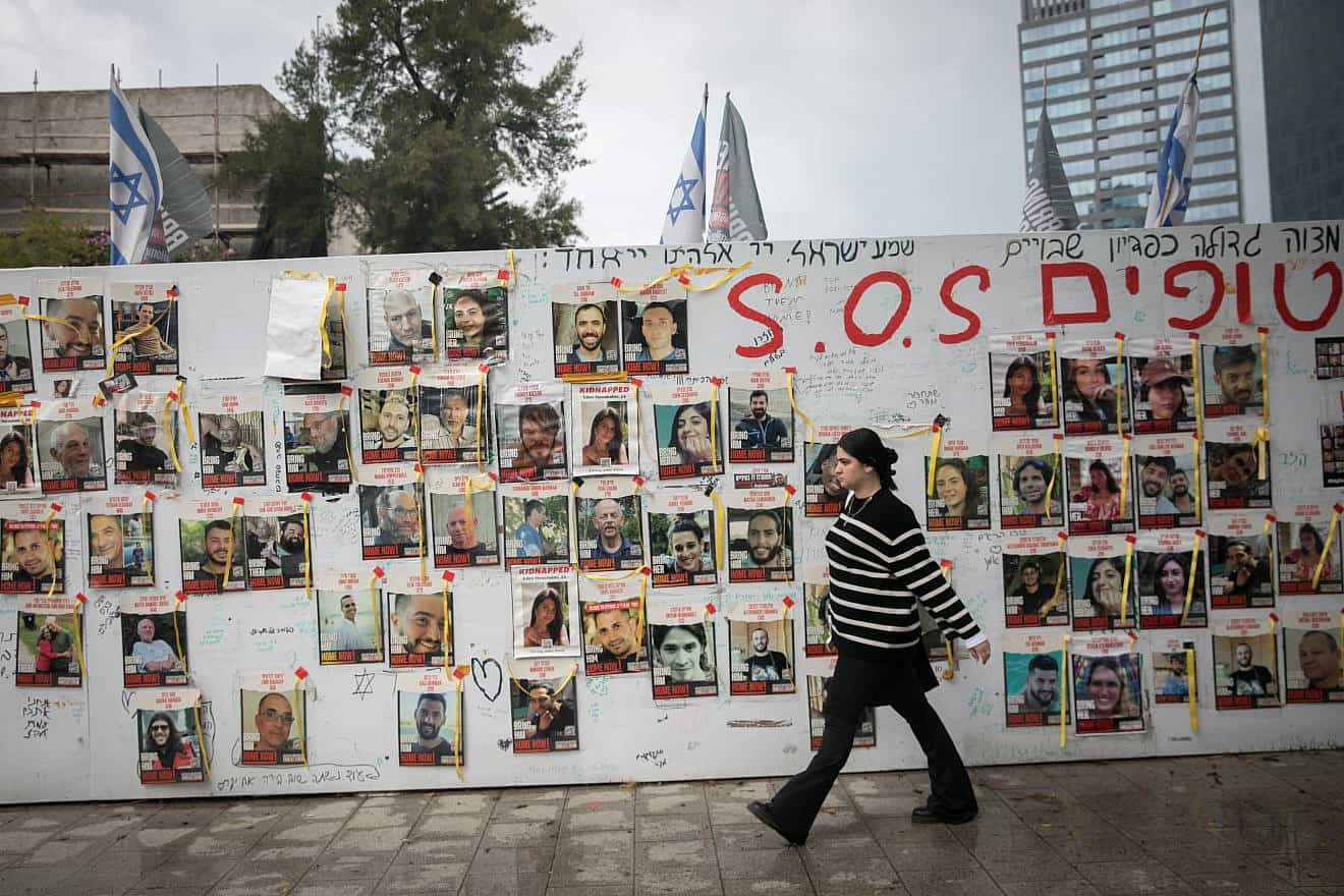 People walk by photographs of Israelis held hostage by Hamas terrorists, in Tel Aviv, March 19, 2024. Photo by Miriam Alster/Flash90.